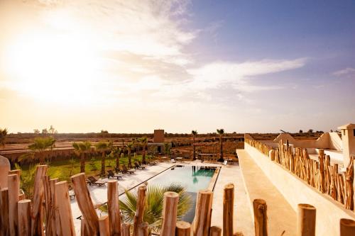 a pool in a resort with a fence and trees at Aghmat Lodge Guest house in Marrakech