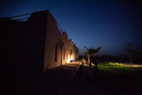 a building lit up at night with a palm tree next to it at Aghmat Lodge Guest house in Marrakech