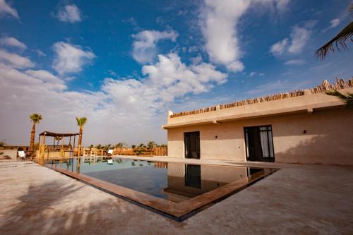a building with a swimming pool in front of it at Aghmat Lodge Guest house in Marrakech