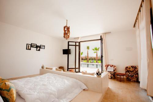 a bedroom with a white bed and a large window at Aghmat Lodge Guest house in Marrakech