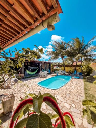 a swimming pool in a yard with palm trees at Aloha Beach Guest House in Maragogi