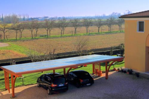 two cars parked under a solar array on a patio at Agriturismo Il Melograno in Tessera