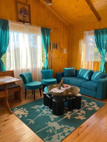 sala de estar con sofá azul y mesa en Cabañas Agroturismo Pupelde, en Ancud