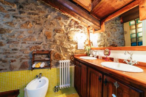 baño con 2 lavabos y pared de piedra en Casa Rural Palacio, en Linares de Mora