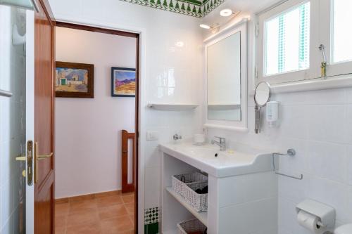 a white bathroom with a sink and a mirror at Famara Caracolillos, La Casa in Famara