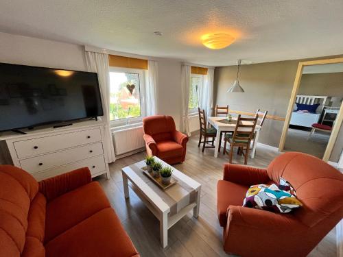 a living room with orange furniture and a dining room at Ferienwohnung Nordbrise in Schashagen