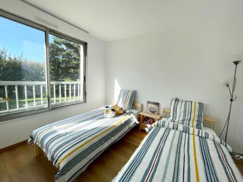 a bedroom with two beds and a large window at Friendly Bean in Cachan