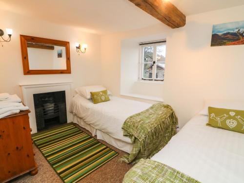 ウルバーストンにあるFurnace Cottageのベッド2台と暖炉付きの部屋