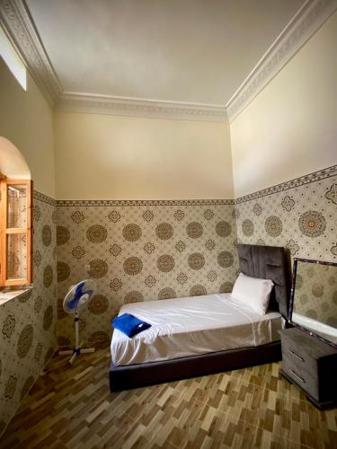 een slaapkamer met een bed in een kamer met behang bij Dar Haniya in Rabat