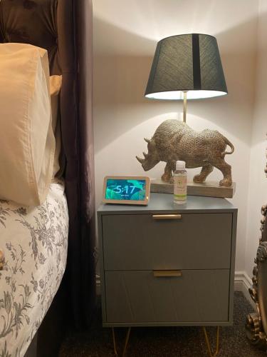 einen Nachttisch mit einer Lampe und einem Bild von einem Schwein drauf in der Unterkunft Niv’s Home away from Home in Kempston