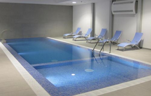 uma piscina com cadeiras azuis num quarto em Hotel Mira Sagres em Vila do Bispo