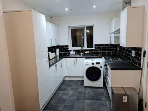 a white kitchen with a washing machine in it at Impeccable 4-Bed House Near Manchester City Centre in Manchester