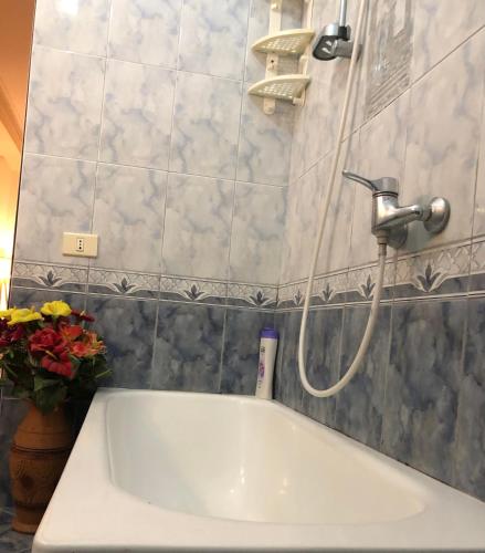 a white bath tub in a bathroom with flowers at Vogli's House Apartments & Rooms in Durrës
