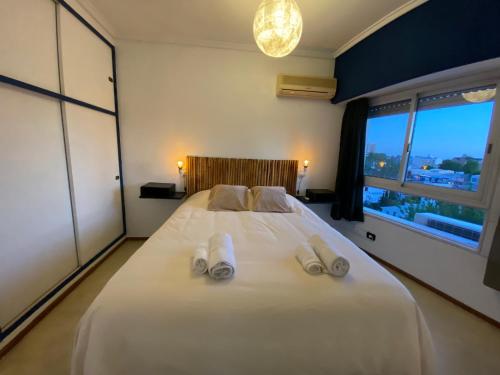 1 dormitorio con 1 cama blanca grande y zapatillas. en Tigre Tower F - Seguridad y tranquilidad en Tigre