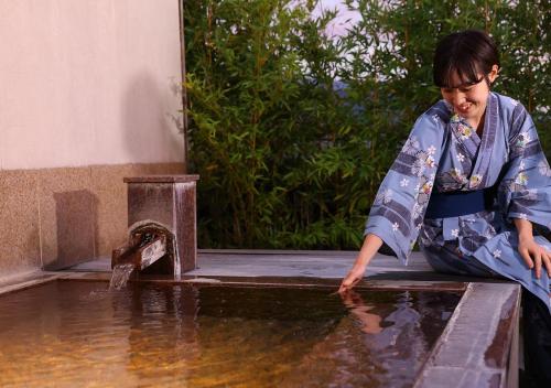 a young child in a kimono playing with water at Hotel Tamanoyu in Matsumoto