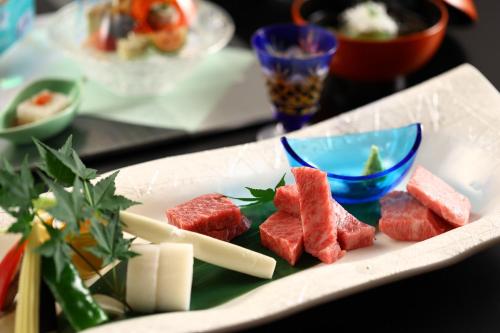 a plate of food on a table with food at Hotel Tamanoyu in Matsumoto