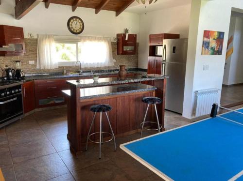 a kitchen with a counter and stools in it at Casa con vista a las sierras de Cordoba in Malagueño