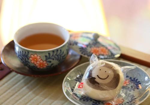 a cup of tea and a plate with a smiley face on it at Hotel Tamanoyu in Matsumoto