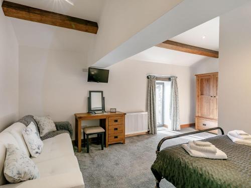 a bedroom with a bed and a couch and a desk at The Barn in Mellor