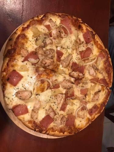 a pizza with ham and cheese on a table at Chekesh Casa in Siquijor