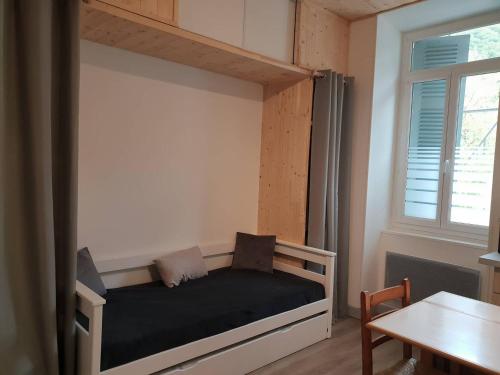 Ce lit se trouve dans un dortoir doté d'une table et d'une fenêtre. dans l'établissement Studio rénové pour 4 pers à 50m du télécabine - FR-1-234-293, à Cauterets