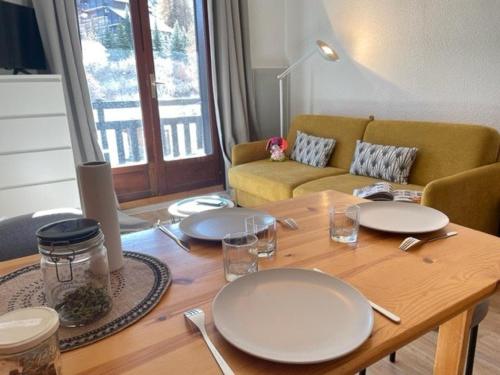 - une table en bois avec des assiettes dans le salon dans l'établissement Studio cabine, 4 pers, Risoul, proche commerces, Cuisine équipée, Balcon, Animaux acceptés - FR-1-330-559, à Risoul