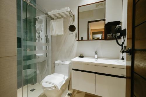 a bathroom with a toilet and a sink and a shower at El Bien Hotel Tagaytay in Tagaytay