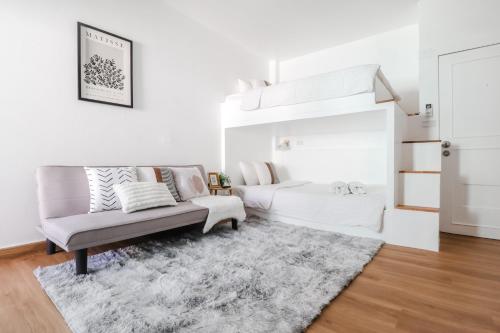 a white living room with a couch and a rug at Link Mansion in Chiang Mai