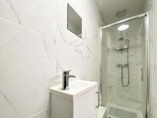 a white bathroom with a sink and a shower at House 1905 - Self Catering Serviced Apartment in North Tidworth