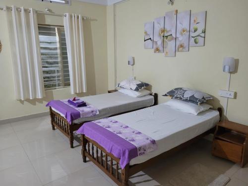 2 Betten in einem Zimmer mit lila Decken in der Unterkunft Sandy beach hotel in Thiruvananthapuram