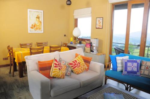 ein Wohnzimmer mit einer weißen Couch mit bunten Kissen in der Unterkunft Kandy Hindagala Retreat - Boutique Villa in Kandy Hills Sri Lanka in Kamburadeniya