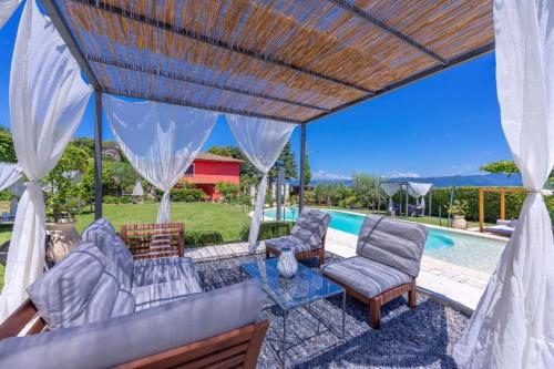 un patio con sillas, una mesa y una piscina en La Casa Fra gli Ulivi - Piscina e natura, relax vicino al mare tra Cinque Terre e Toscana en Monte Marcello