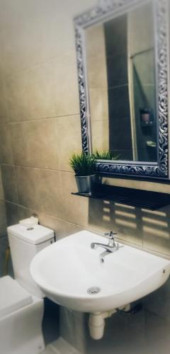 a bathroom with a toilet and a sink and a mirror at My Dallyne's Homestay at Mutiara Ville Cyberjaya in Cyberjaya