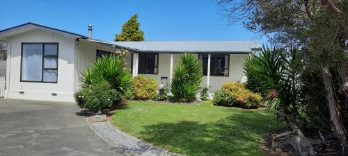 a white house with trees and plants in front of it at Cosy on Courtney in Motueka