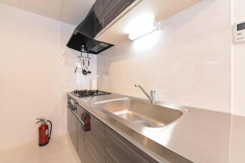 a kitchen with a sink and a stove at GLASS Yamahana EAST in Minami-jūichijō