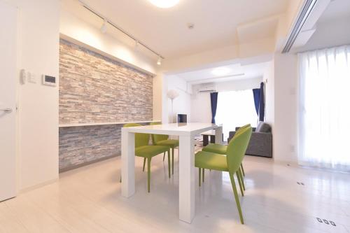 a dining room with a white table and green chairs at GLASS Yamahana EAST in Minami-jūichijō