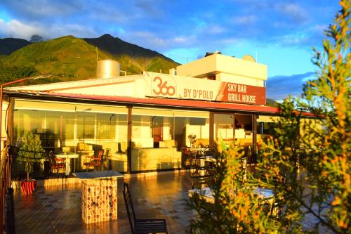 a building with a restaurant with a mountain in the background at Hotel 360 by D'Polo Dharamshala in Dharmsala