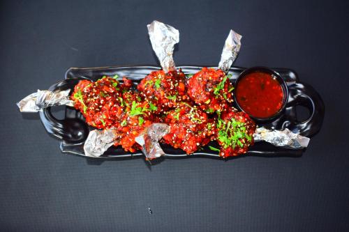 a black plate of food with meat and broccoli at Hotel 360 by D'Polo Dharamshala in Dharmsala