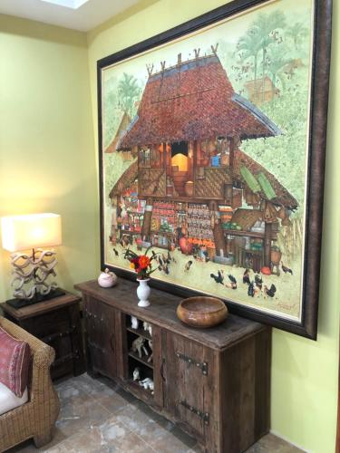 a painting of a house on the wall in a living room at On The Mekong Resort in Luang Prabang