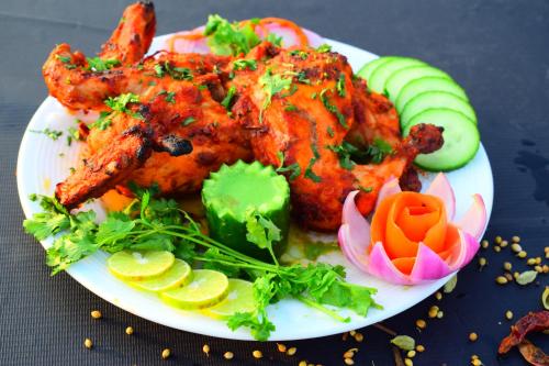 a plate of food with chicken and vegetables on a table at Hotel 360 by D'Polo Dharamshala in Dharmsala