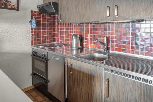 ベットマーアルプにあるMinerva Antaresの赤いタイル張りの壁、シンク付きのキッチンが備わります。