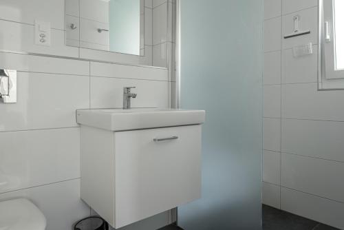 W białej łazience znajduje się umywalka i lustro. w obiekcie Kirschstein OG w mieście Fiesch