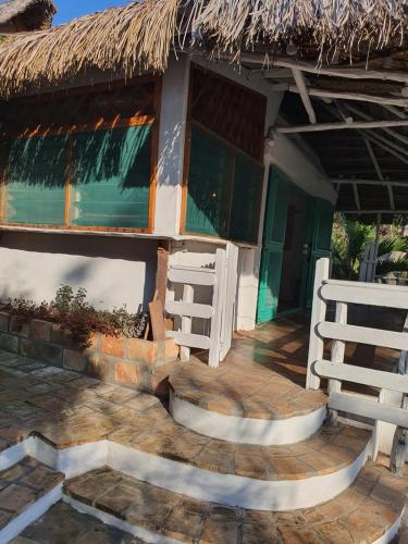 a house with a thatched roof and a wooden porch at Sunset View Tofo in Praia do Tofo