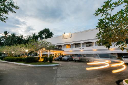 a building with cars parked in a parking lot at The Mercy Hotel in Chumphon
