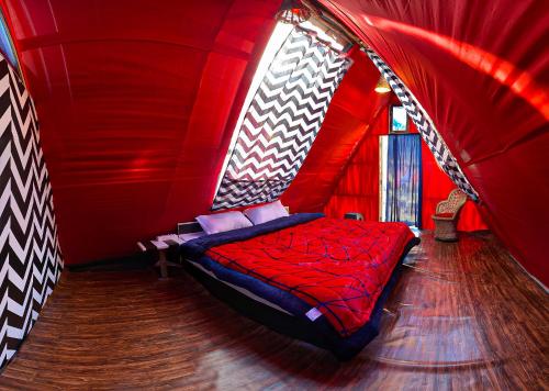 1 dormitorio con cama roja en una tienda roja en TravelON Manali Glamping Resort en Manāli