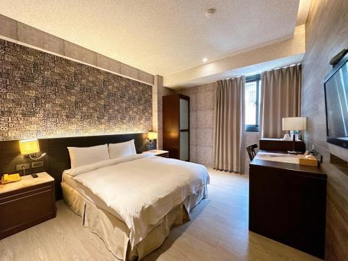 a hotel room with a bed and a television at DLInn Hotel in Taichung