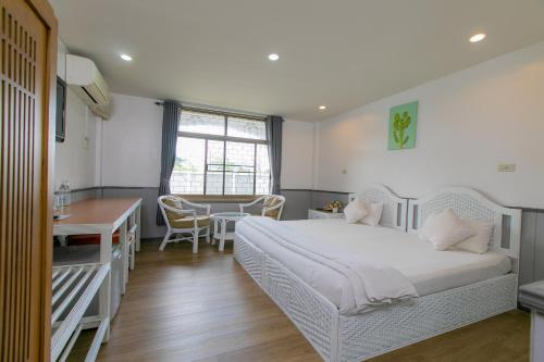 a bedroom with a bed and a desk and a table at The Mercy Hotel in Chumphon