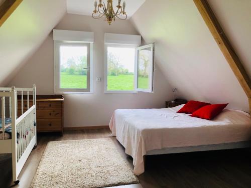 a bedroom with a bed with red pillows and two windows at LE PETIT MARAIS in Clais