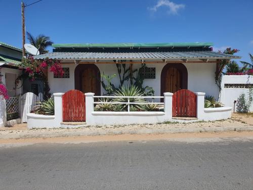 a white house with red doors and a fence at Sunset View Tofo in Praia do Tofo