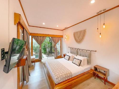 a bedroom with a bed and a flat screen tv at Villa Casa Koko in Gili Islands